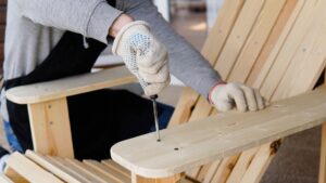 Close-up of hands in gloves assembling a wooden chair frame