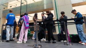 A group of people queuing outside a store, with one person wearing an Airtasker T-shirt